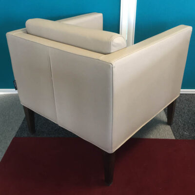 Fauteuil de marque TACCHINI en cuir beige, coussins amovibles, reposant sur 4 pieds droits en bois teinté foncé. 70 x 68 x 71 cm.