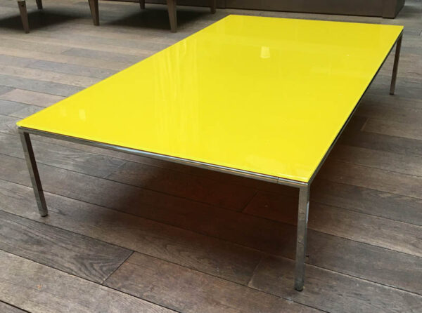 Table basse rectangulaire, plateau en verre teinté jaune, cadre et piètement en acier chromé. (usures). 30 x 140 x 80 cm.