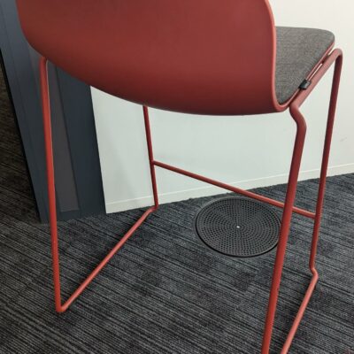 Tabouret haut empilable design Fredrik Mattson modèle Neo Lite édition MATERIA, coque en plastique rouge avec galette d’assise en tissu gris reposant sur un piètement luge en acier laqué rouge avec repose-pied. 84 x 44 x 44 cm. Localisation : 5ème