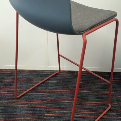 Tabouret haut empilable design Fredrik Mattson modèle Neo Lite édition MATERIA, coque en plastique bleu pétrole avec galette d’assise en tissu gris reposant sur un piètement luge en acier laqué rouge avec repose-pied. 84 x 44 x 44 cm. Localisation : 5ème