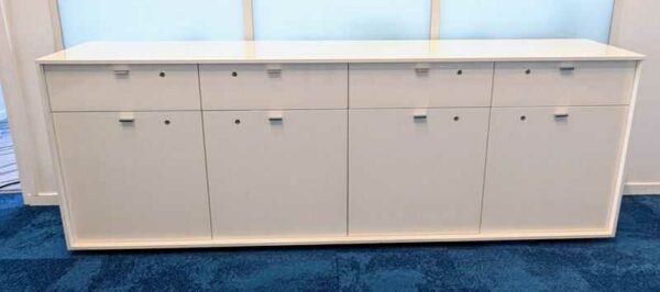 Armoire basse ou enfilade en bois laqué blanc ouvrant par 4 tiroirs et 4 portes battantes. 87 x 244 x 49 cm. Localisation : 7 ouest