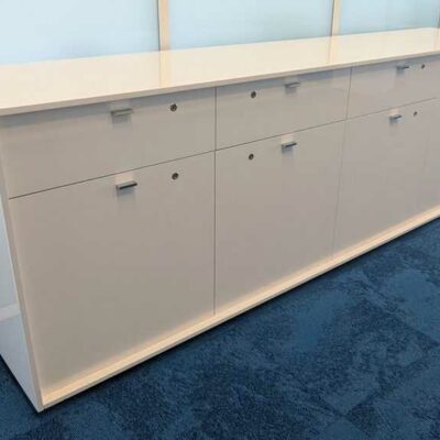Armoire basse ou enfilade en bois laqué blanc ouvrant par 4 tiroirs et 4 portes battantes. 87 x 244 x 49 cm. Localisation : 7 ouest