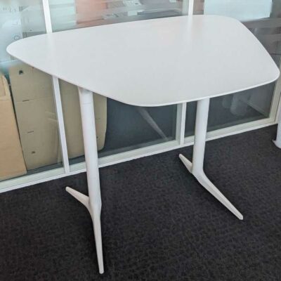 Table haute de marque EFE en bois stratifié blanc à plateau trapézoïdal reposant sur 2 pieds en acier laqué blanc. 71 x 140 x 110 cm. Localisation : 7 ouest