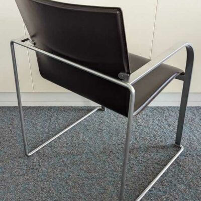 Suite de 6 fauteuils de marque LAPALMA, armature en acier brossé, garniture en cuir marron, piètement luge. 80 x 57 x 57 cm. Localisation : 7 est