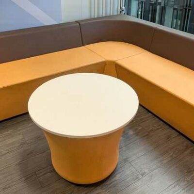 Espace d’attente de marque Connection comprenant 3 banquettes et 1 table ronde, en simili cuir orange et marron. 70 x 240 x 200 x 70 cm. Localisation : 5 ouest