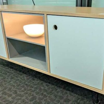 Meuble bas en bois couleur chêne clair avec une niche et 2 portes en bois laqué blanc ouvrant sur 1 étagère, piètement en épingle en acier laqué noir. 50 x 110 x 40 cm. Localisation : 5 ouest