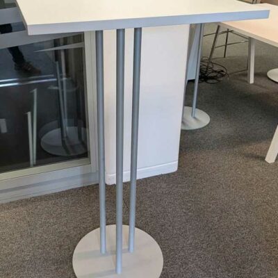 2 tables hautes à plateau carré en bois stratifié blanc reposant sur 3 pieds en métal sur base circulaire. 110 x 60 x 60 cm. Localisation : 3 est