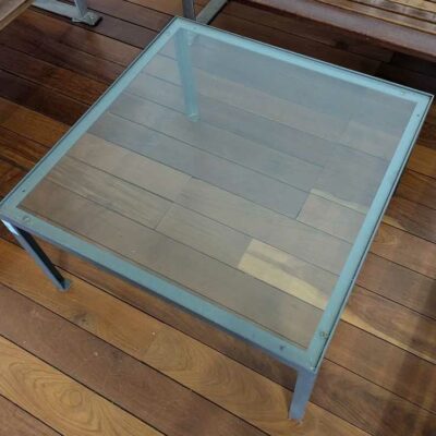 Table basse structure en fonte d’acier, plateau carré en verre transparent. 40 x 73 x 73 cm. Localisation : Canada hall