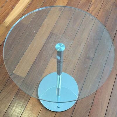 Table d’appoint en acier chromé et insert en bois, plateau rond en verre transparent (rayures). 65 x 45 cm. Localisation : Canada hall