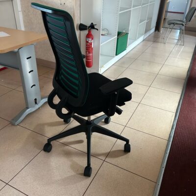 Fauteuil de bureau assise en tissu noir dossier en résille verte piètrement noir sur roulettes