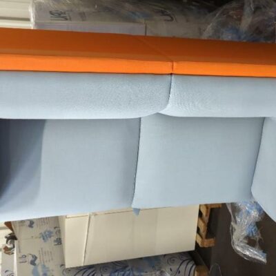 Canapé de marque Connection recouvert de tissu bicolore orange et gris clair, 4 pieds en acier chromé. 76 x 162 x 77 cm. Localisation : 8 rue de la Fossé aux Leux 91700 Ste Geneviève des Bois