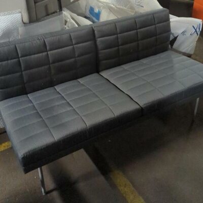 Canapé de marque Geiger modèle Tuxedo recouvert de tissu matelassé gris, piètement en métal. 77 x 142 x 70 cm. Localisation : 8 rue de la Fossé aux Leux 91700 Ste Geneviève des Bois