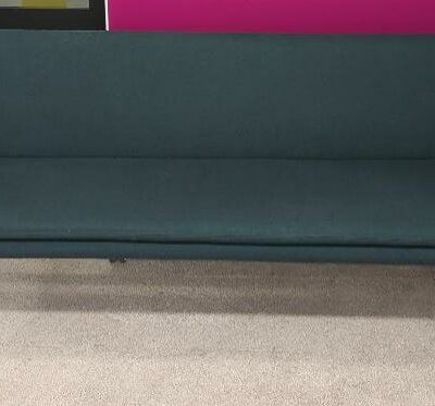 Canapé de marque Bolia recouvert de feutrine vert bouteille, coussin d’assise amovible, piètement en bois naturel. 77 x 202 x 57 cm. Localisation : 9 avenue Percier 75008 Paris