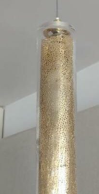 Trois suspensions lumineuses, base en laiton, tube en verre transparent renfermant une feuille stylisée en métal doré. 66 x 7 cm. (Belgrand 6e)