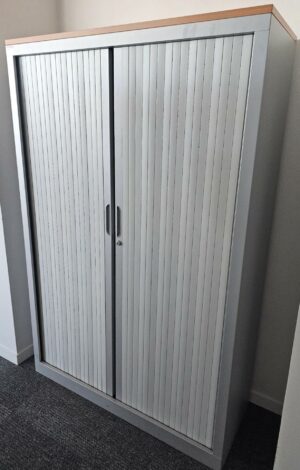 Armoire haute à porte rideaux coulissantes, couleur grise et top en bois couleur bois miel. Dimensions: 180 x 120 X 45 cm. Quantités disponibles: 750 unités. Localisation : 8 av. de Lunca - 78180 Montigny-le-Bretonneux.