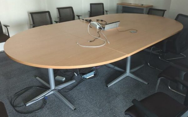Table de réunion de forme ovale en 3 parties, plateau en bois stratifié couleur hêtre avec trappe technique, piètement en acier laqué gris. 75 x 320 x 180 cm. Localisation : 8 av. de Lunca - 78180 Montigny-le-Bretonneux. (5F02-1)