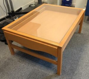 Table basse en bois avec tiroir coulissant et plateau en verre transparent. 45 x 105 x 80 cm. Localisation : 8 av. de Lunca - 78180 Montigny-le-Bretonneux. (salon expat)