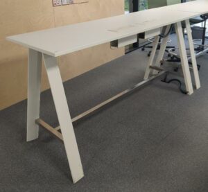 Table haute rectangulaire avec deux trappes passe câbles, plateau en bois, piètement en acier laqué blanc. 105 x 210 x 70 cm. 3 unités. Vendu à l'unité avec faculté de réunion. rdc