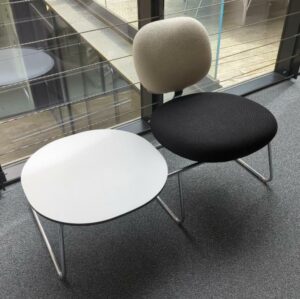 Espace d'attente design Jasper Morrison modèle Vega comprenant un siège recouvert de tissu noir et blanc et une table basse, plateau rond en bois blanc, structure en acier chromé. Largeur 114 cm. 2eme