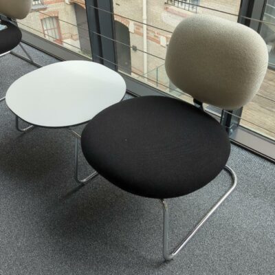 Espace d’attente design Jasper Morrison modèle Vega comprenant un siège recouvert de tissu noir et blanc et une table basse, plateau rond en bois blanc, structure en acier chromé. Largeur 114 cm. 2eme