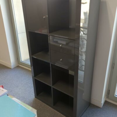 Meuble bibliothèque en bois laqué gris à 8 compartiments dont 1 porte et 2 tiroirs. 
unités : 6
es8, 1er haut, 3-82, 3-71, 515b