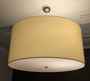 Suspension lumineuse de marque MODO modèle Cilindro, abat-jour en tissu blanc cassé, 3 ampoules, disque en plexiglas. Dimensions abat-jour : 36 x 67 cm. 32 unités. Vendu à l'unité avec faculté de réunion. Localisation : 2 est, 3 est, 4 est, 5 est, 5 ouest, 6 est, 6 ouest.