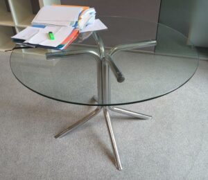 Table ronde plateau en verre transparent reposant sur un piètement à 4 branches en acier tubulaire chromé. 71 x 110 cm. Vendu à l'unité avec faculté de réunion Localisation : 1-37