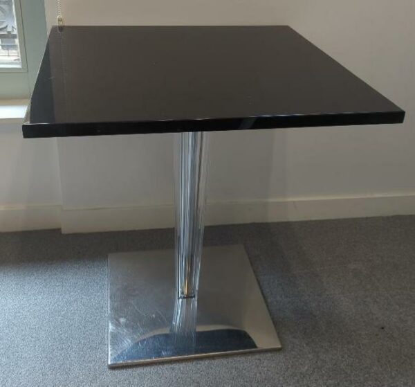 Table à plateau carré en bois laqué noir reposant sur un piètement en plexiglas biseauté, base en acier chromé. (usures). 73 x 70 x 70 cm. Localisation : 6 rue Duret - 75116 Paris : es 15