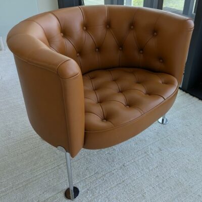 Fauteuil design Trix & Robert Haussmann modèle Haussmann édition Walter Knoll, revêtement en cuir capitonné marron, piètement en acier tubulaire chromé sur patins. 70 x 72 x 85 cm. Localisation : 7 ouest (7712)