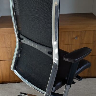 Fauteuil de direction pivotant ajustable avec tétière de marque TALIN, structure en acier chromé, dossier en résille, garniture en cuir marron foncé, piètement en étoile à 5 branches sur roulettes. Localisation : 7 ouest (7712)