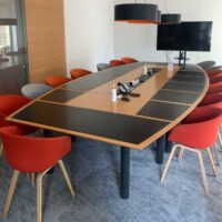 Table de réunion, en bois, avec un plateau en forme de tonneau, trappes techniques et surfaces antidérapantes noires, sur piétements en métal.
72 x 480 x 220 cm.
Localisation : 6 rue Duret - 75116 Paris, 
(RDC haut salle Pékin.) – Image 3
