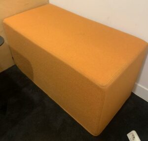 Banquette de marque Buzzi Space modèle BuzziCube recouverte de tissu orange. 46 x 92 x 47 cm. Localisation : 10 rue Petit - 75019 Paris (1er)