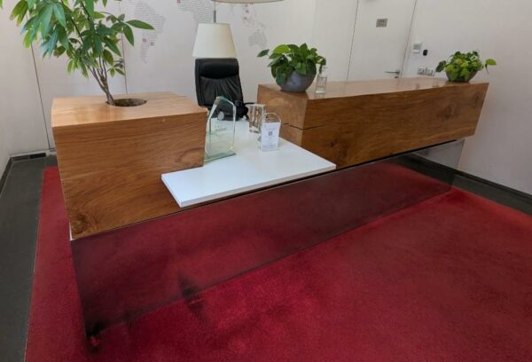 Comptoir ou banque d'accueil composé d'un billot de bois découpé et plaque de métal en partie basse côté public, et un espace de travail en bois stratifié blanc avec niches et étagères côté privé. 110 x 330 x 130 cm. Localisation : 6 rue Duret - 75116 Paris (hall)