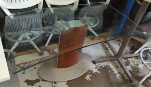 Bureau plateau de forme concave en verre transparent reposant sur un pied central en bois et métal. 73 x 134 x 70 cm. Localisation : 10 rue du Ballon - 93160 Noisy-le-Grand