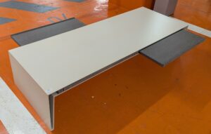 Table basse rectangulaire en métal couleur beige, avec 2 tirettes en bois cérusé noir. 38 x 180 x 65 cm. Localisation : 5 avenue Kleber - 75116 Paris