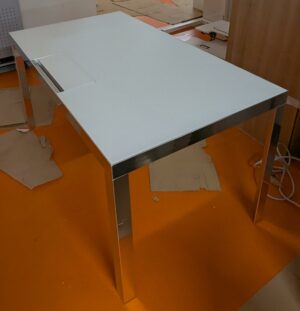 Bureau rectangulaire de marque Unifor, plateau en bois stratifié et verre avec trappe technique, piètement chromé. 74 x 140 x 80 cm. Localisation : 5 avenue Kleber - 75116 Paris